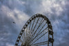 High in the sky, a jet plane passes above the Capital Wheel at National Harbor.