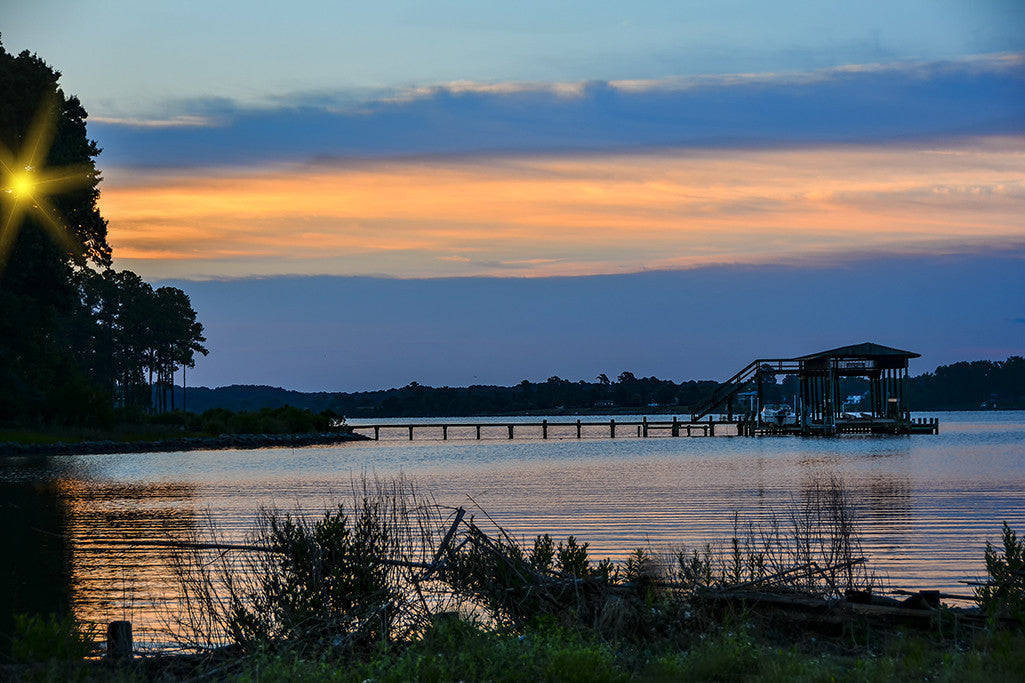 The sun peeks through the trees just after dawn along the Corrotoman River in Lancaster Virginia.