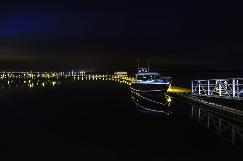 A cabin cruiser is docked in Cambridge Maryland on a calm Summer night.