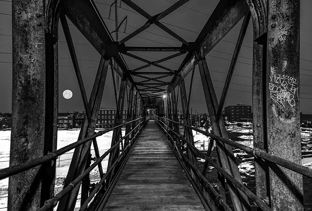 A full moon is framed by an elevated pedestrian walkway.
