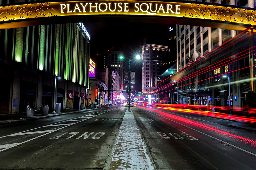 A long exposure photograph captures the light trails of a streaking transit bus as it passes on Euclid Avenue in downtown Cleveland.